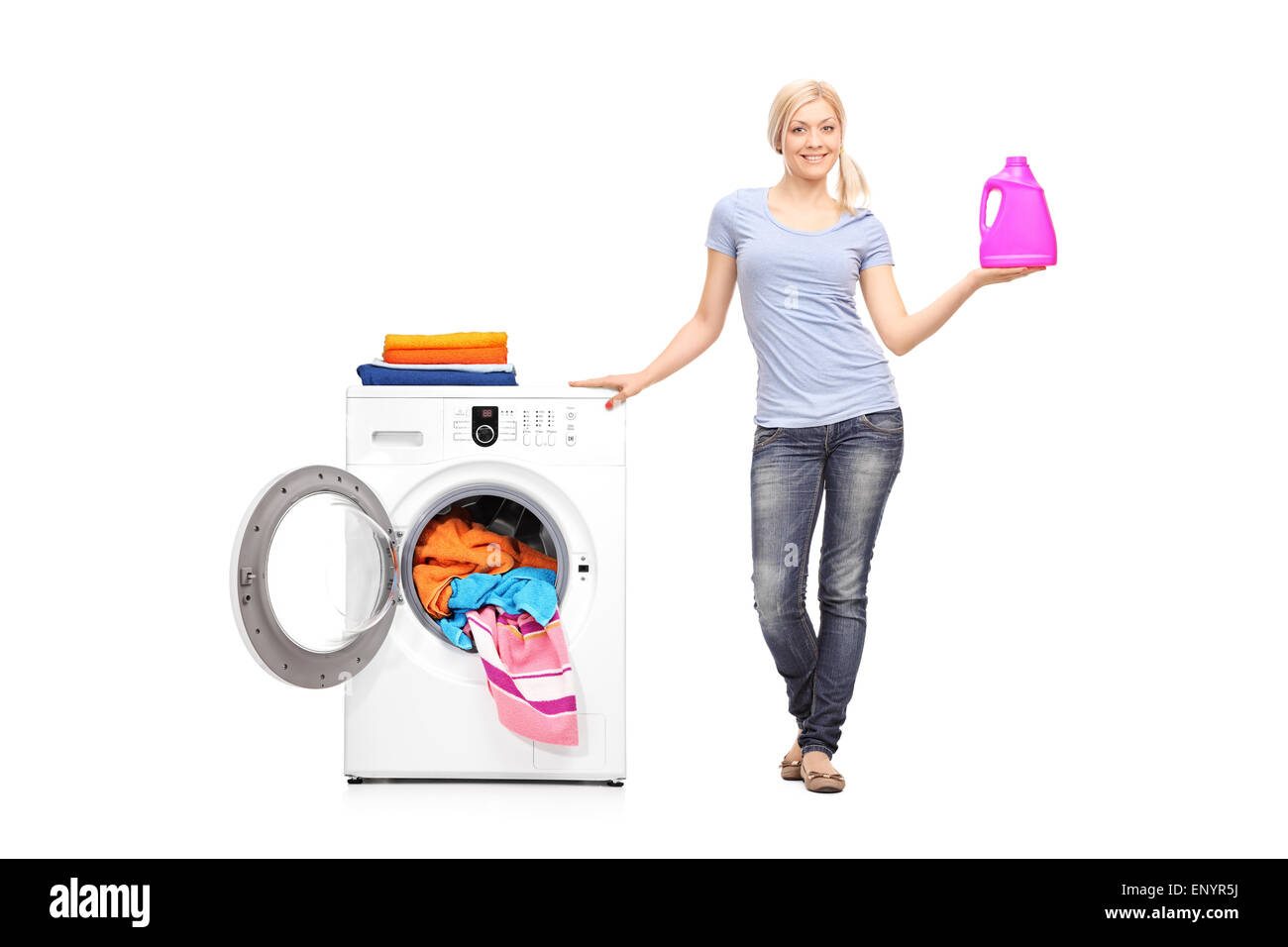 Full length portrait of a young woman holding a washing detergent and posing next to a washing machine Stock Photo