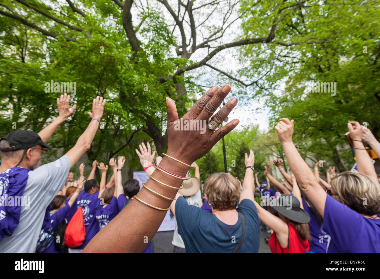 Members and supporters of the group Milagros Day Worldwide raise their hands prior to their their Mother's Day Walk against domestic violence, starting at City Hall in New York on Mother's Day, Sunday, May 10, 2015. Several hundred men, women and children, some of them victims,  participated in their warm up pep rally and walked across the bridge to raise money and awareness for the victims of domestic violence. (© Richard B. Levine) Stock Photo