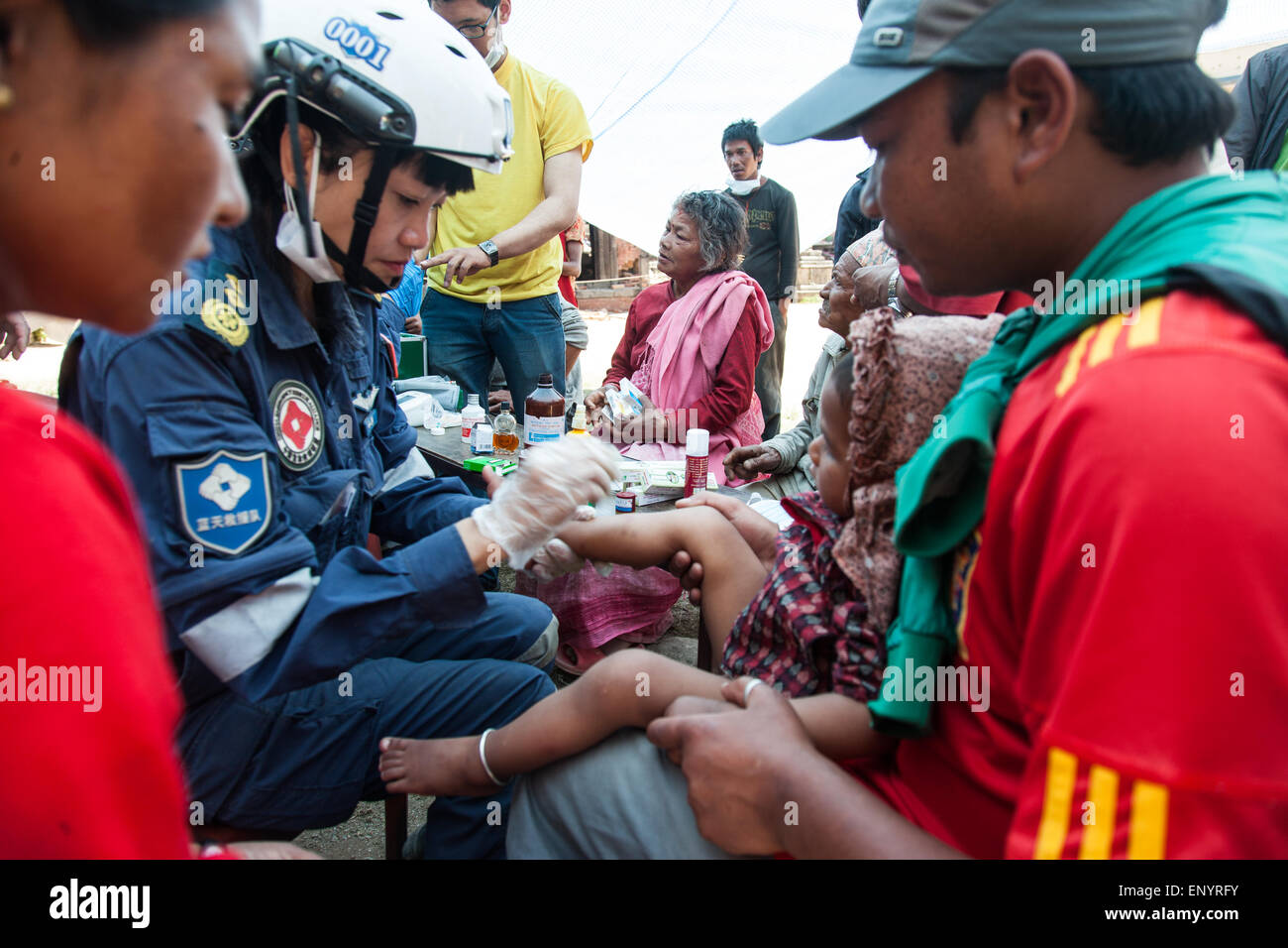 A Chinese doctor treating a child affected by Nepal Earthquake in Sankhu Village. It's been a year and conditions havent changed Stock Photo