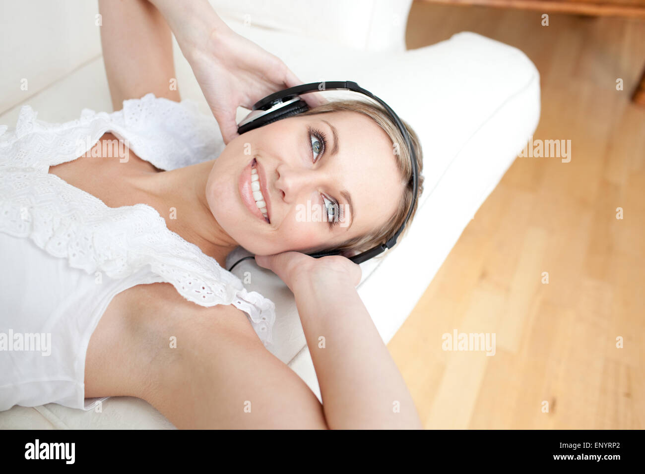 Bright young woman listening music lying on a sofa Stock Photo - Alamy