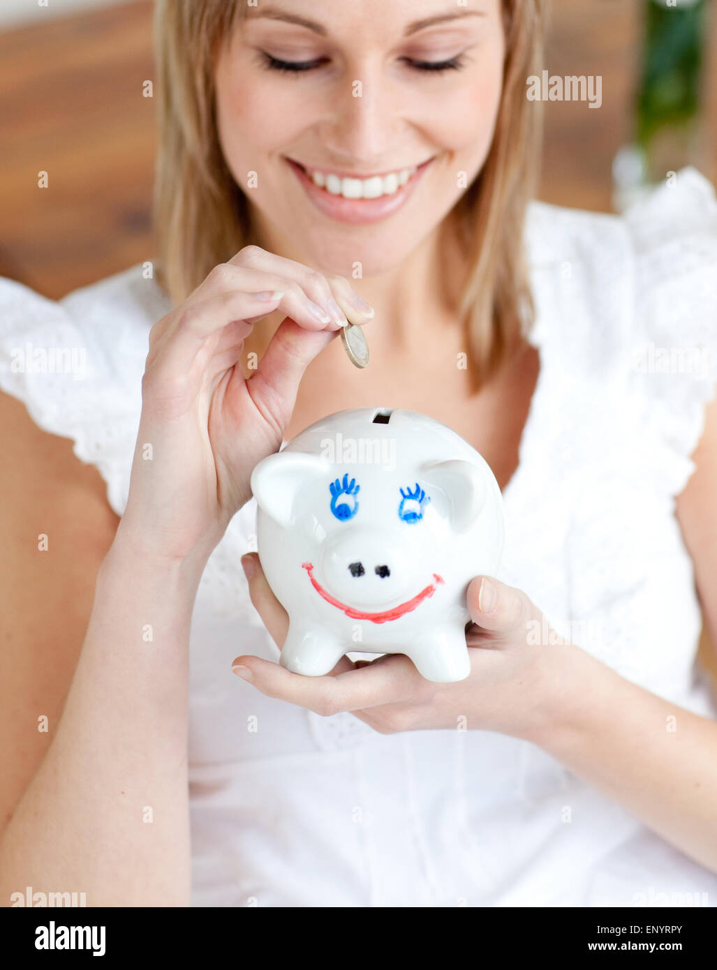 Cheerful woman saving money in a piggy-bank Stock Photo - Alamy