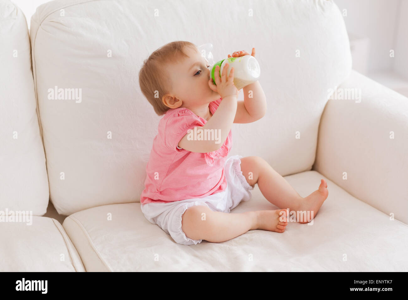 Baby bottlefeeding while sitting on a sofa Stock Photo Alamy