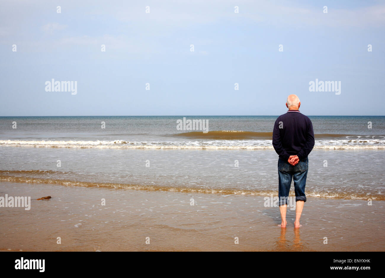 A senior citizen paddling in the sea on the east coast at Happisburgh, Norfolk, England, United Kingdom. Stock Photo