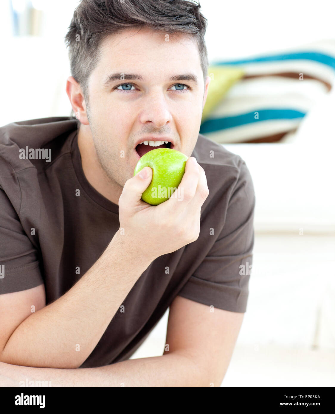 Young man lying on the ground and eating a green apple Stock Photo Alamy