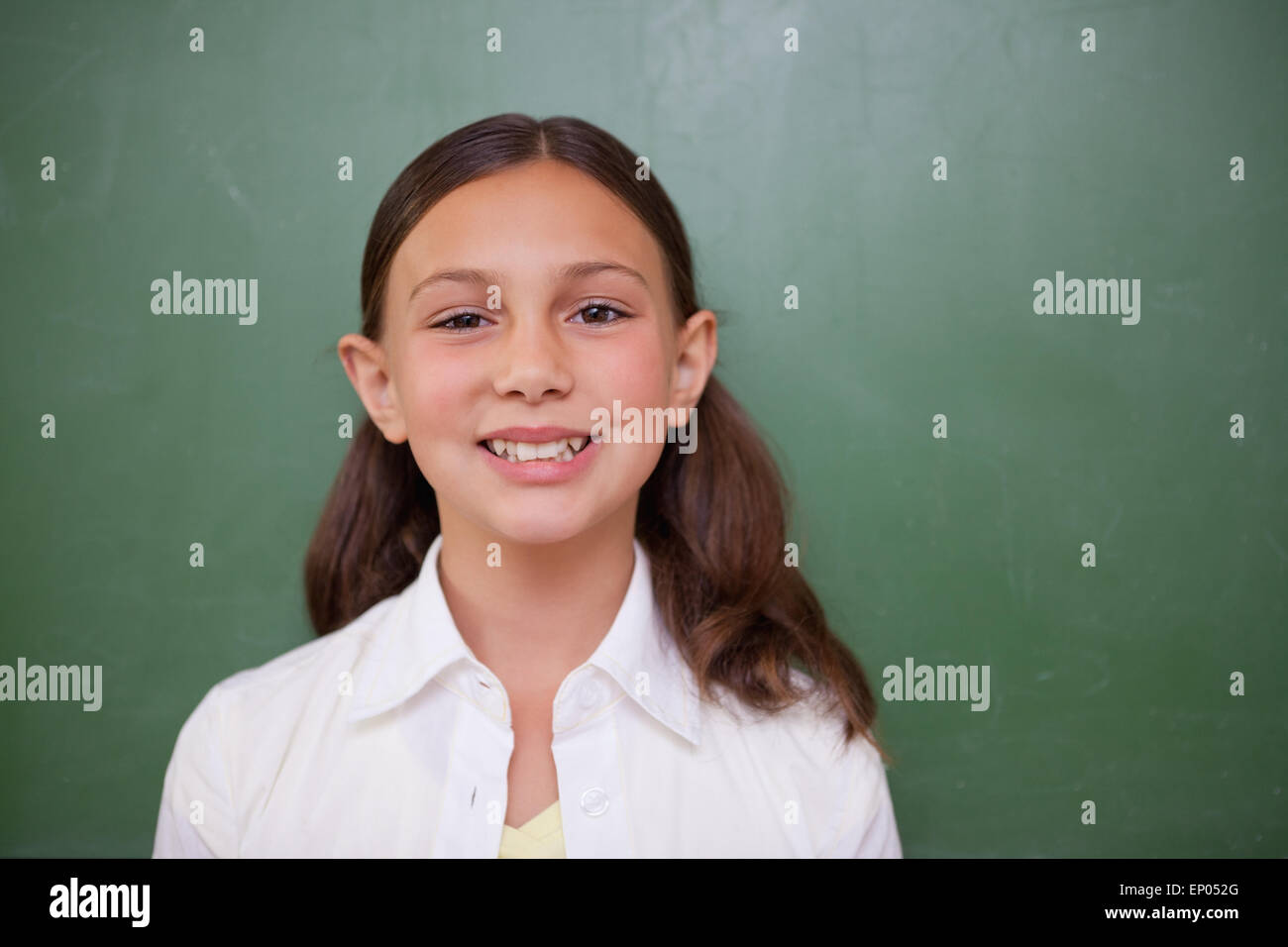 Cute schoolgirl standing in front of a blackboard Stock Photo - Alamy