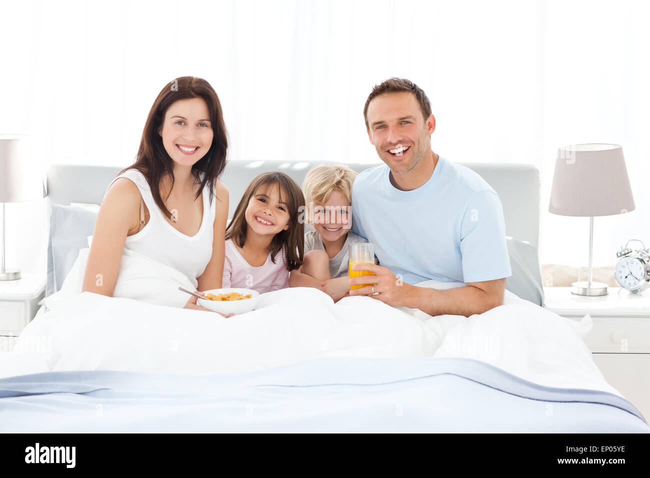 Happy family having breakfast together on the bed Stock Photo - Alamy