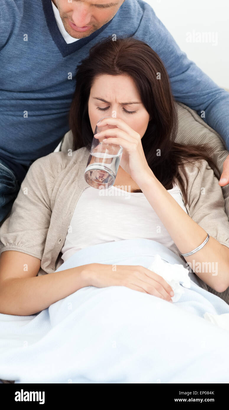 Sick woman drinking water lying on the sofa Stock Photo Alamy