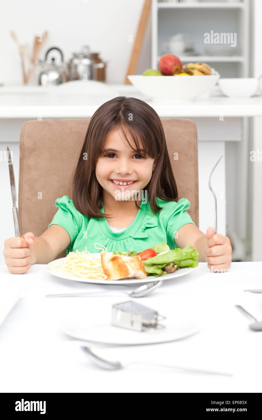 Adorable llittle girl holding forks to eat pasta and salad Stock Photo