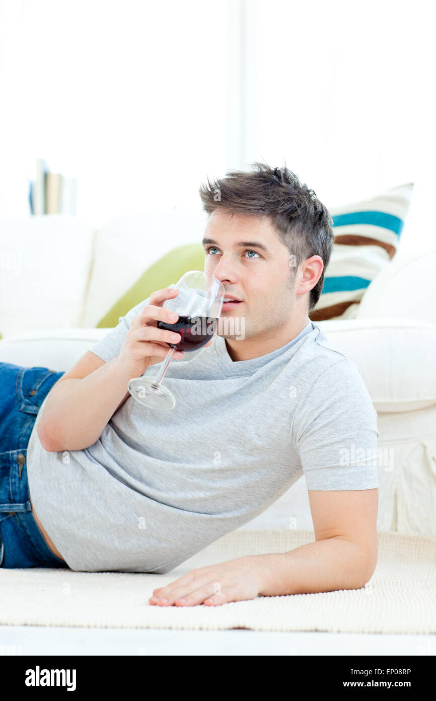 Positive young man drinking wine in the living-room Stock Photo - Alamy