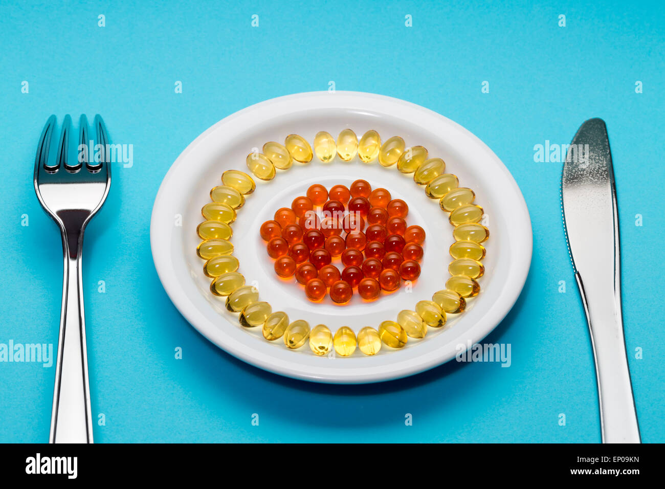 Yellow and red pills on a plate on blue background Stock Photo