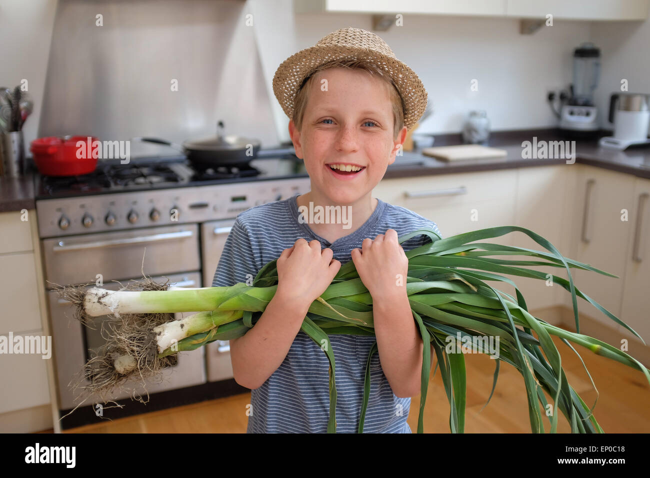 A happy boy with fresh grown organic leeks picked from the garden Stock Photo