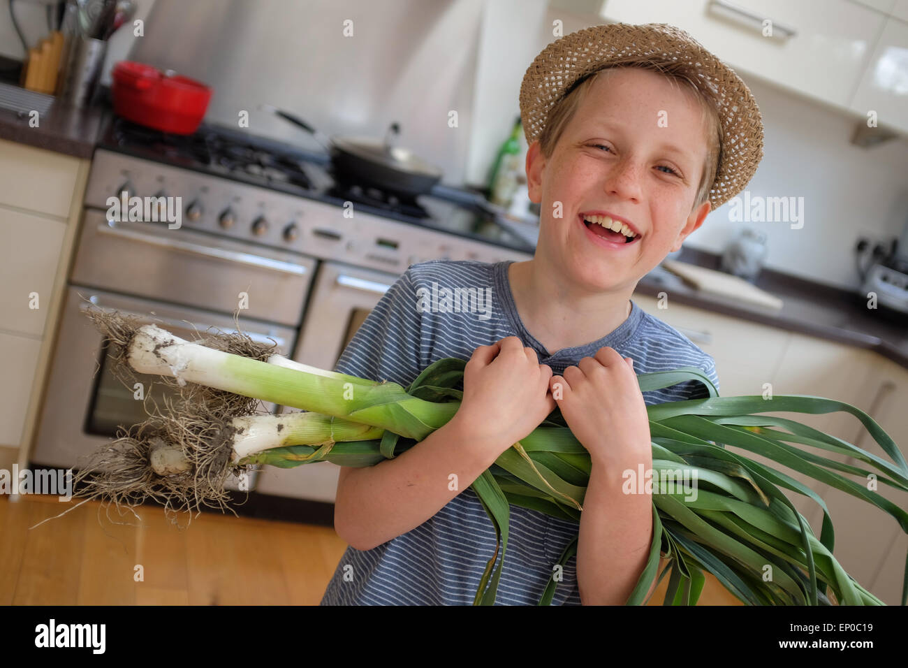 A happy boy with fresh grown organic leeks picked from the garden Stock Photo