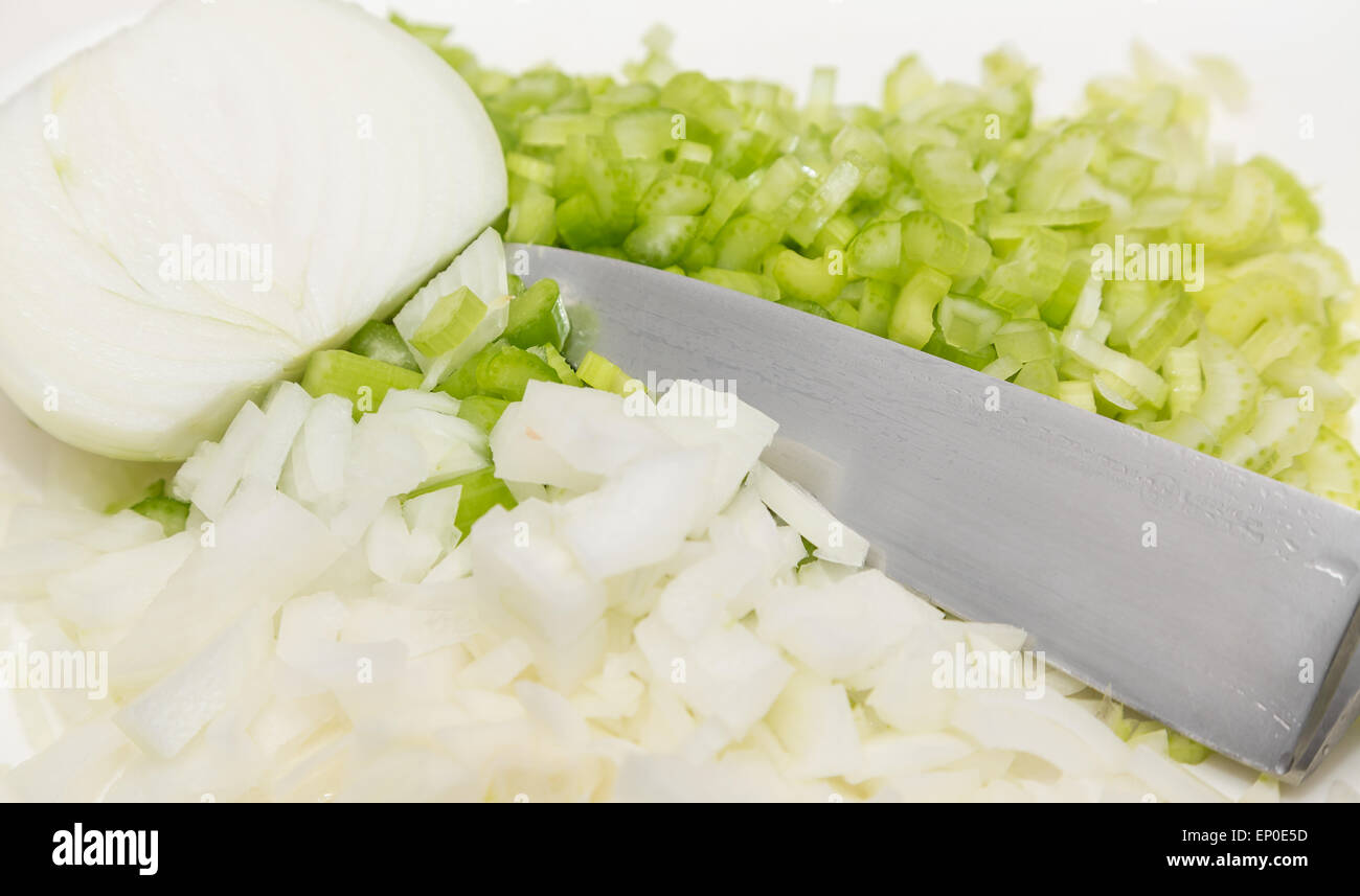 A half onion with chopped onions and celery on cutting board with chef ...
