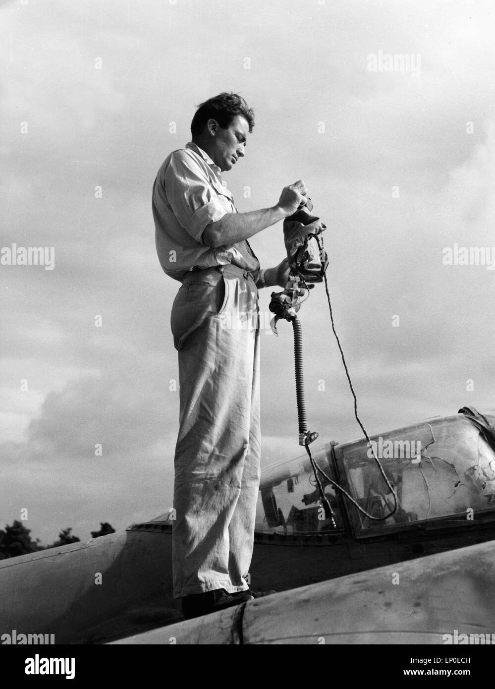 Der amerikanische Schauspieler Gregory Peck richtet seinen Helm für den Film 'Flammen über Fernost' her, 1954. American actor Gr Stock Photo