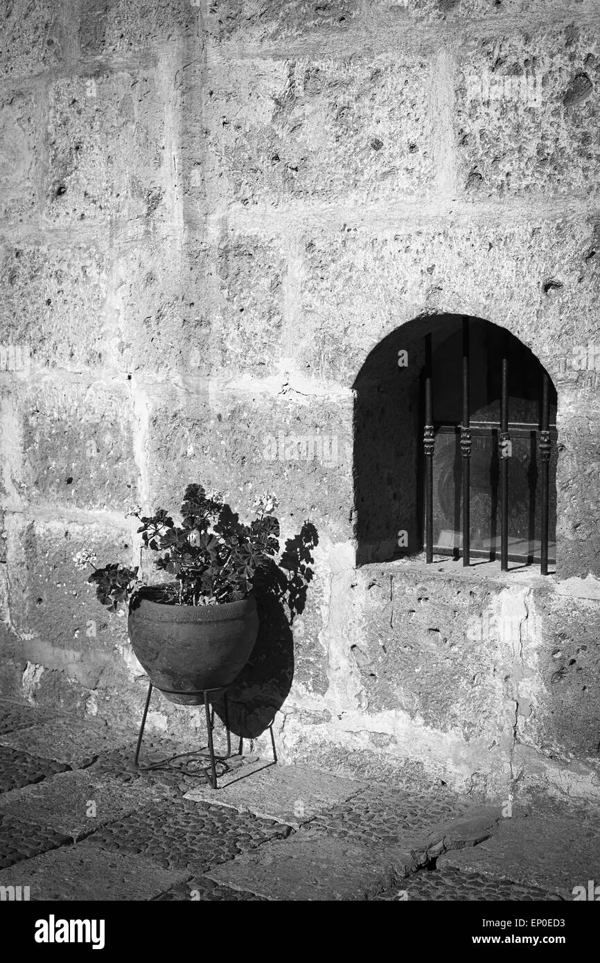 Geranium flowers in plant pot standing next to a small window in courtyard in Arequipa, Peru Stock Photo
