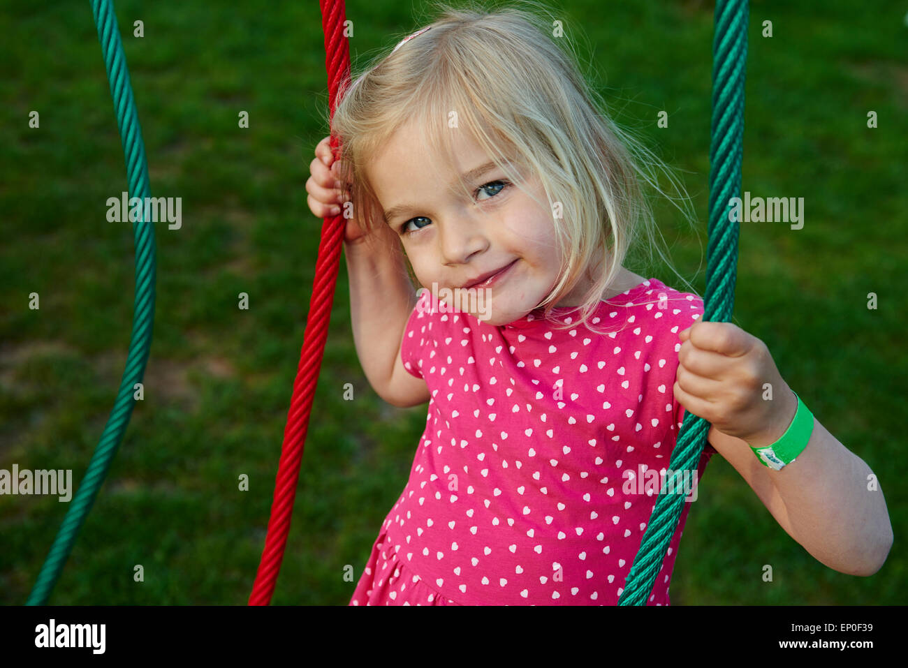 Portrait of child young blond girl climbing ropes on playground Stock Photo