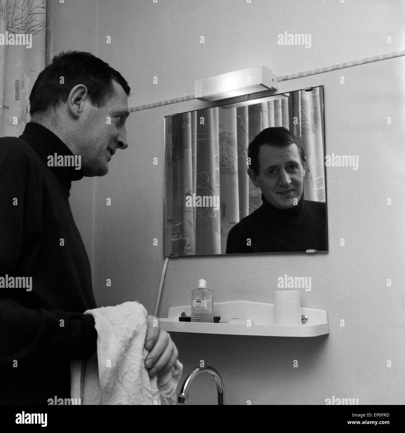 Deutscher Drehbuchautor und Journalist Wolfgang Menge blickt in den Spiegel Badezimmer seines Hotels, Mitte 1960er Jahre. Ger Stock Photo