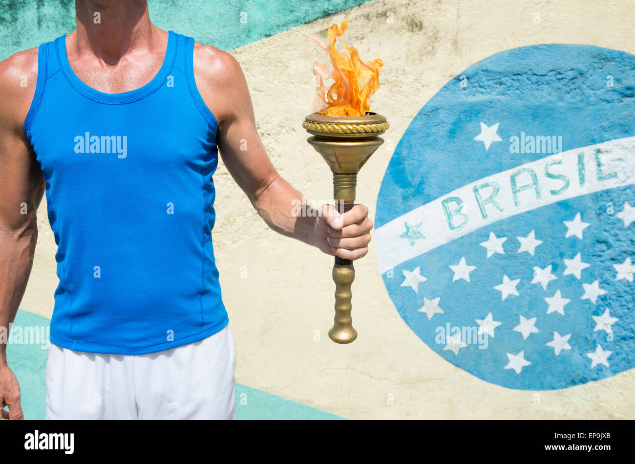 Brazilian athlete holding sport torch standing in front of a Brasil flag mural Rio de Janeiro Brazil Stock Photo