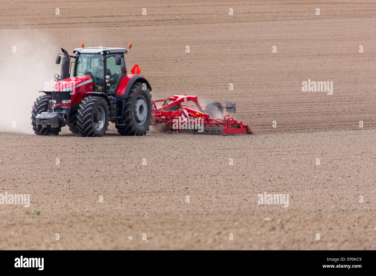 The tractor harrowing the large brown field in spring season Stock ...