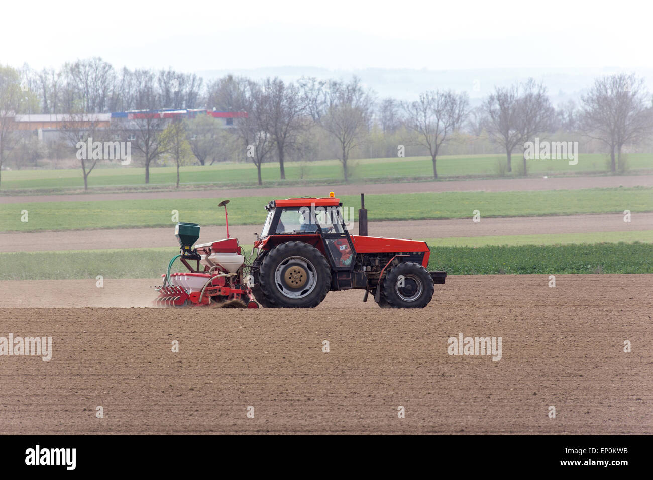 The tractor harrowing the large brown field in spring season Stock ...