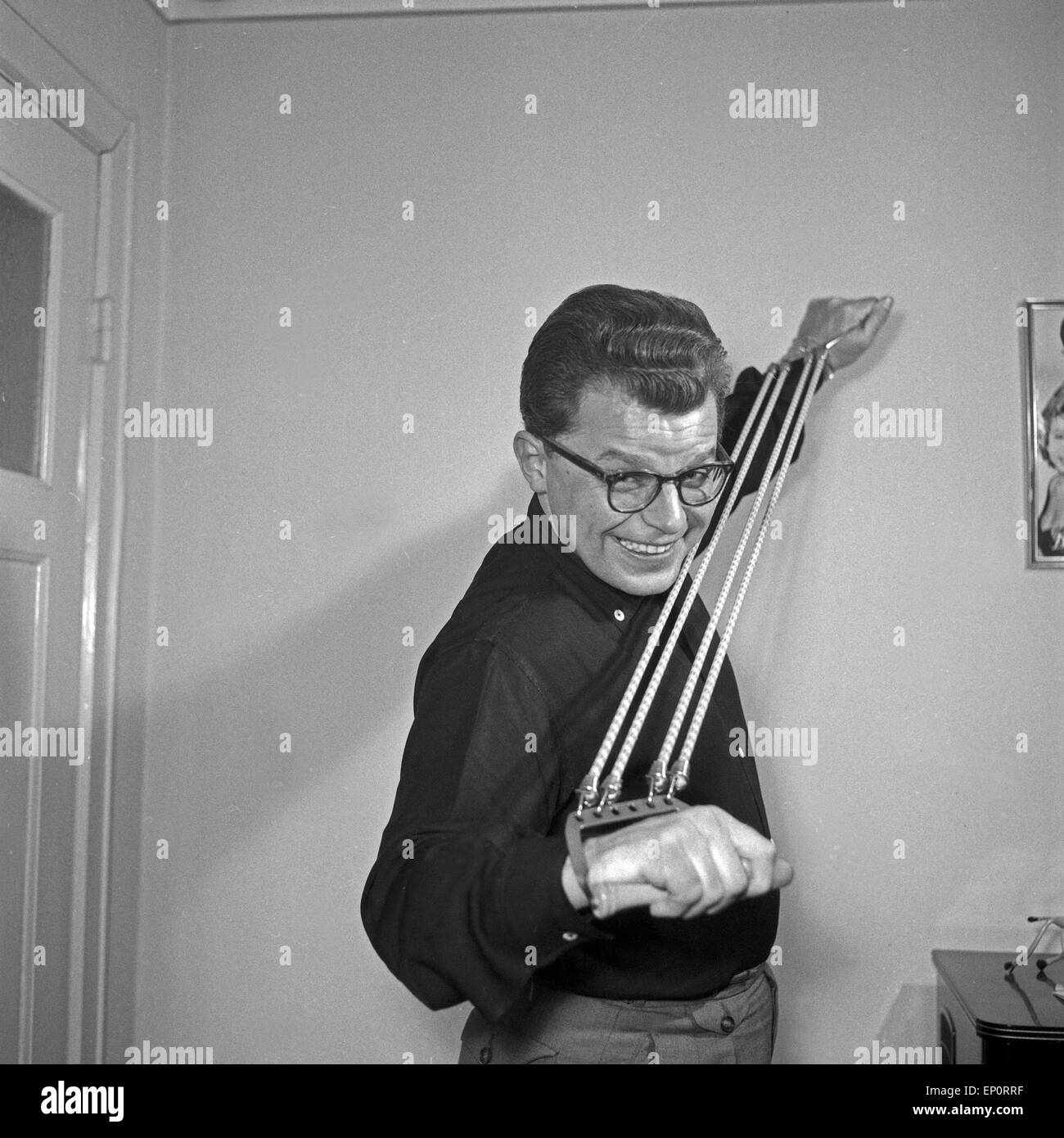 Deutscher Schlagersänger Rolf Simson posiert mit einem Expander, Hamburg 1956. German schlager singer Rolf Simson posing with Stock Photo