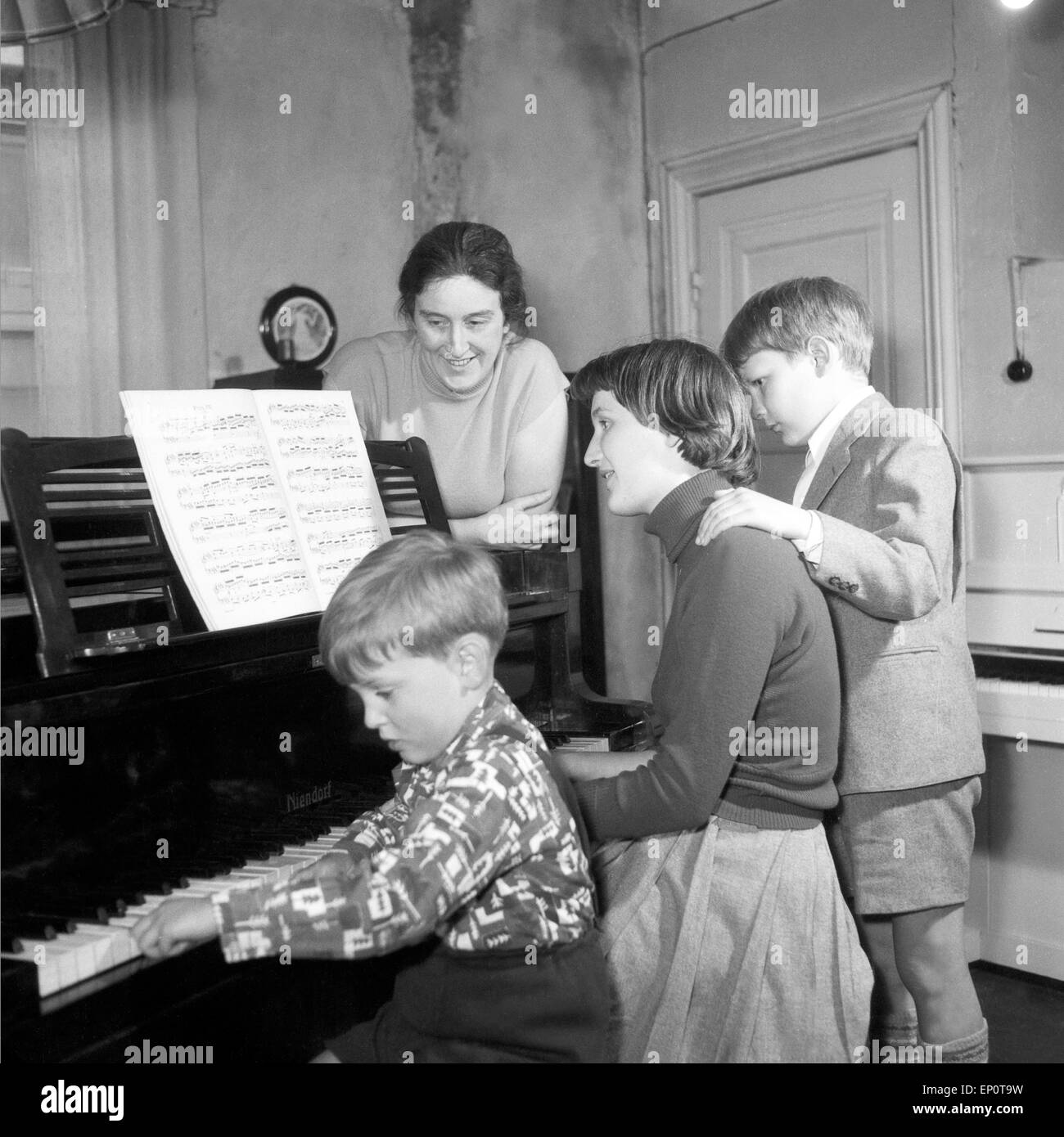 Kinder lernen bei ihrer Klavierlehrerin Klavier spielen, Hamburg 1956. Children learn to play piano with their teacher. Stock Photo