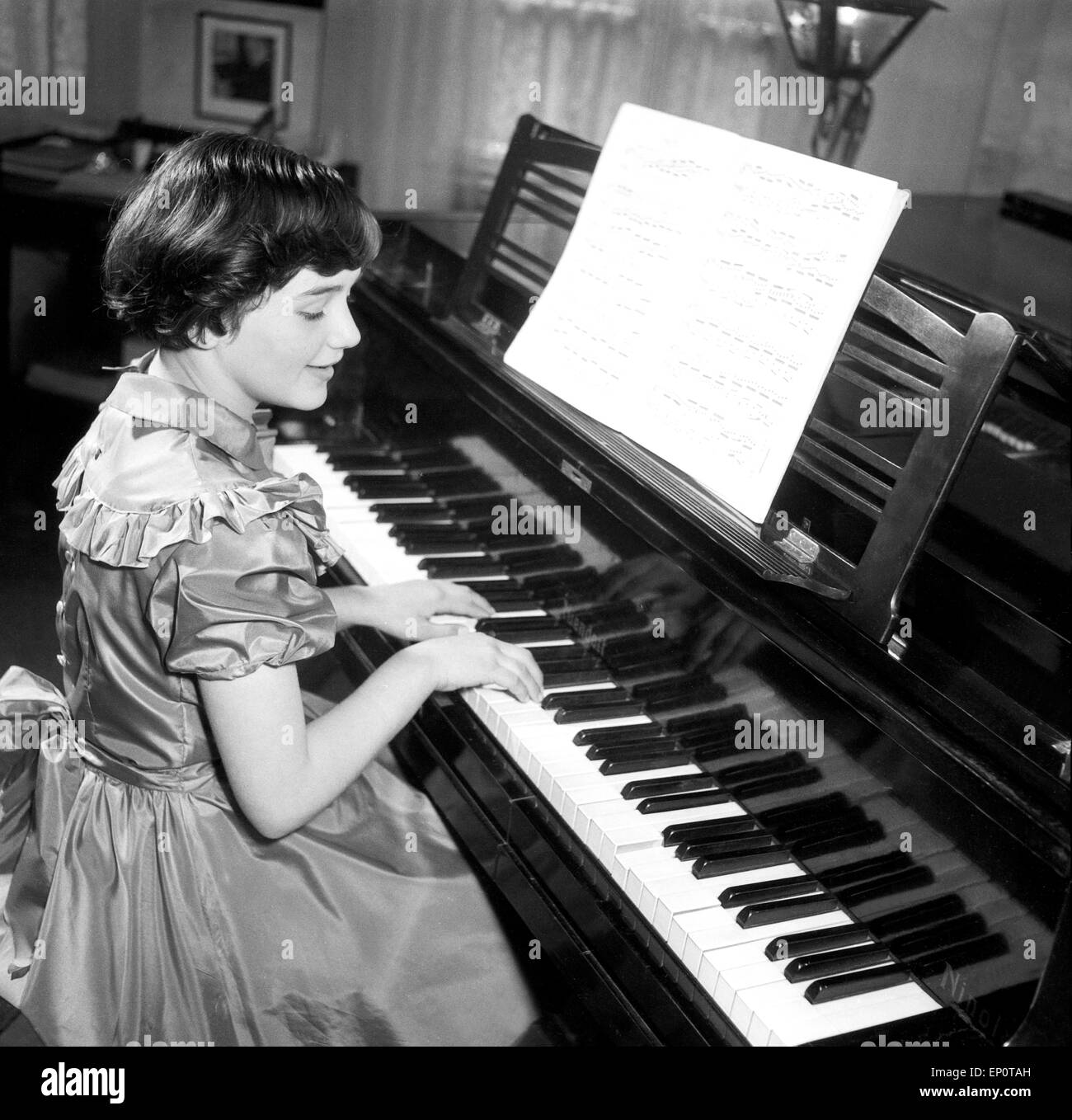 Ein Mädchen spielt an einem Flügel, Hamburg 1956. A little girl playing a grand piano. Stock Photo