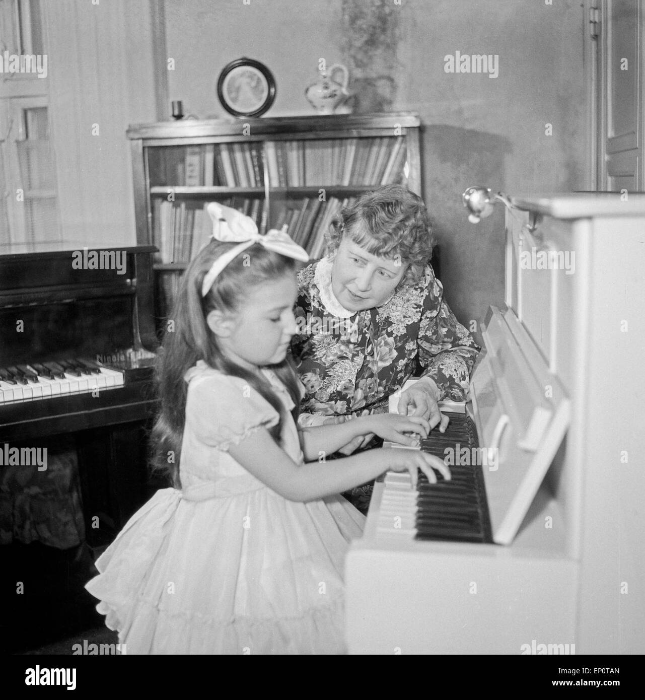 Ein Mädchen spielt an einem Klavier, Hamburg 1956. A little girl playing a piano. Stock Photo