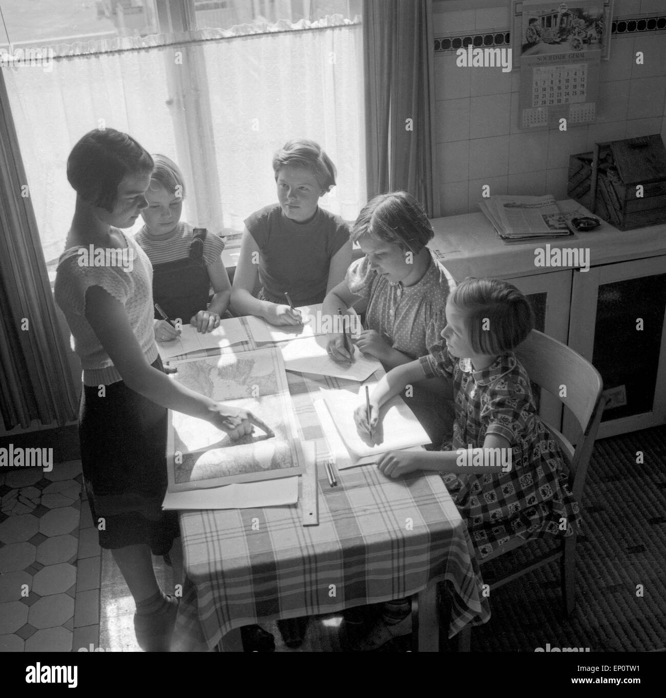 Kinder machen gemeinsam ihre Hausaufgaben in der Küche, Deutschland 1950er Jahre. Five children doing their homework and learnin Stock Photo