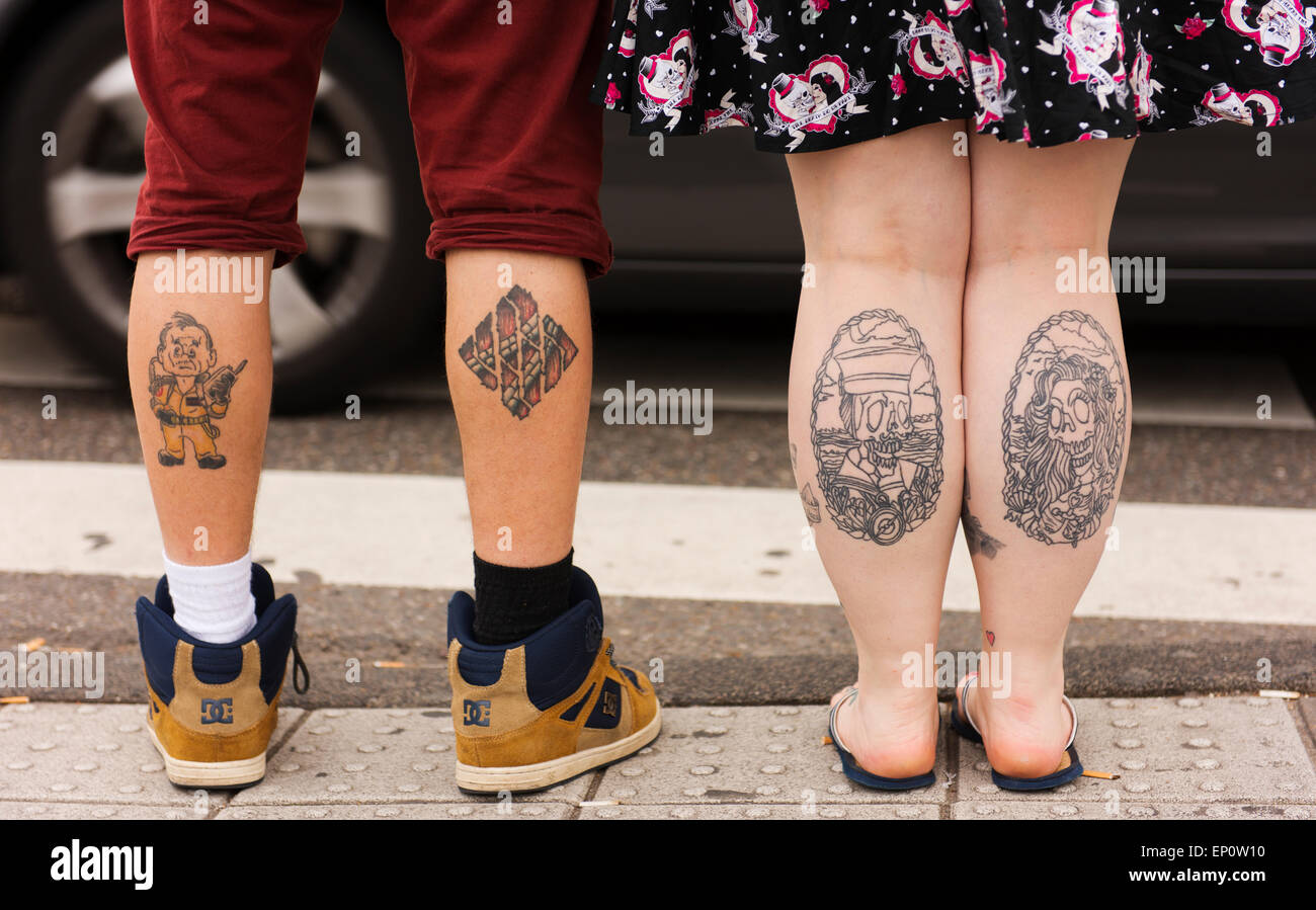 Young couple in Amsterdam's Old Town with tattoos on their calves. Stock Photo