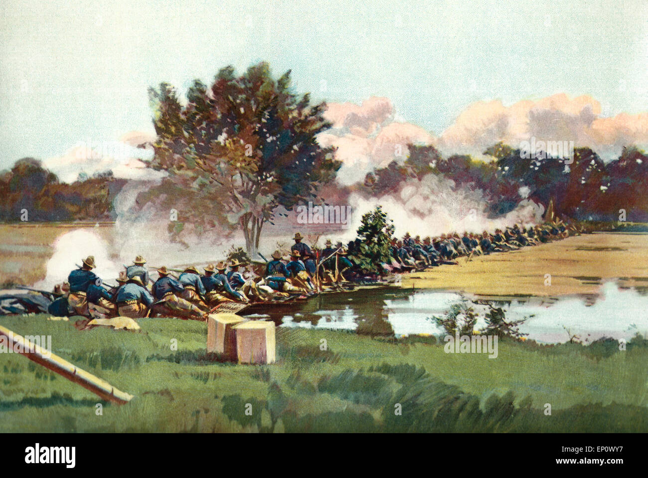 On the Firing Line. 'M' Company, Twentieth Kansas, behind a rice dike in the first position taken February 4, 1899.  THis view was taken about 10 AM, Sunday, February 5, 1899, during heavy fire.  The first man in the regiment to fall in battle was killed at the moment of taking this picture, shot through the head.  His body may be seen about the tenth man from the left.  The Company is in the act of firing a volley.  The effect of Pratt's death may be seen from the fact that the smoke indicates that several men on each side of him failed to fire. Philippine American War Stock Photo