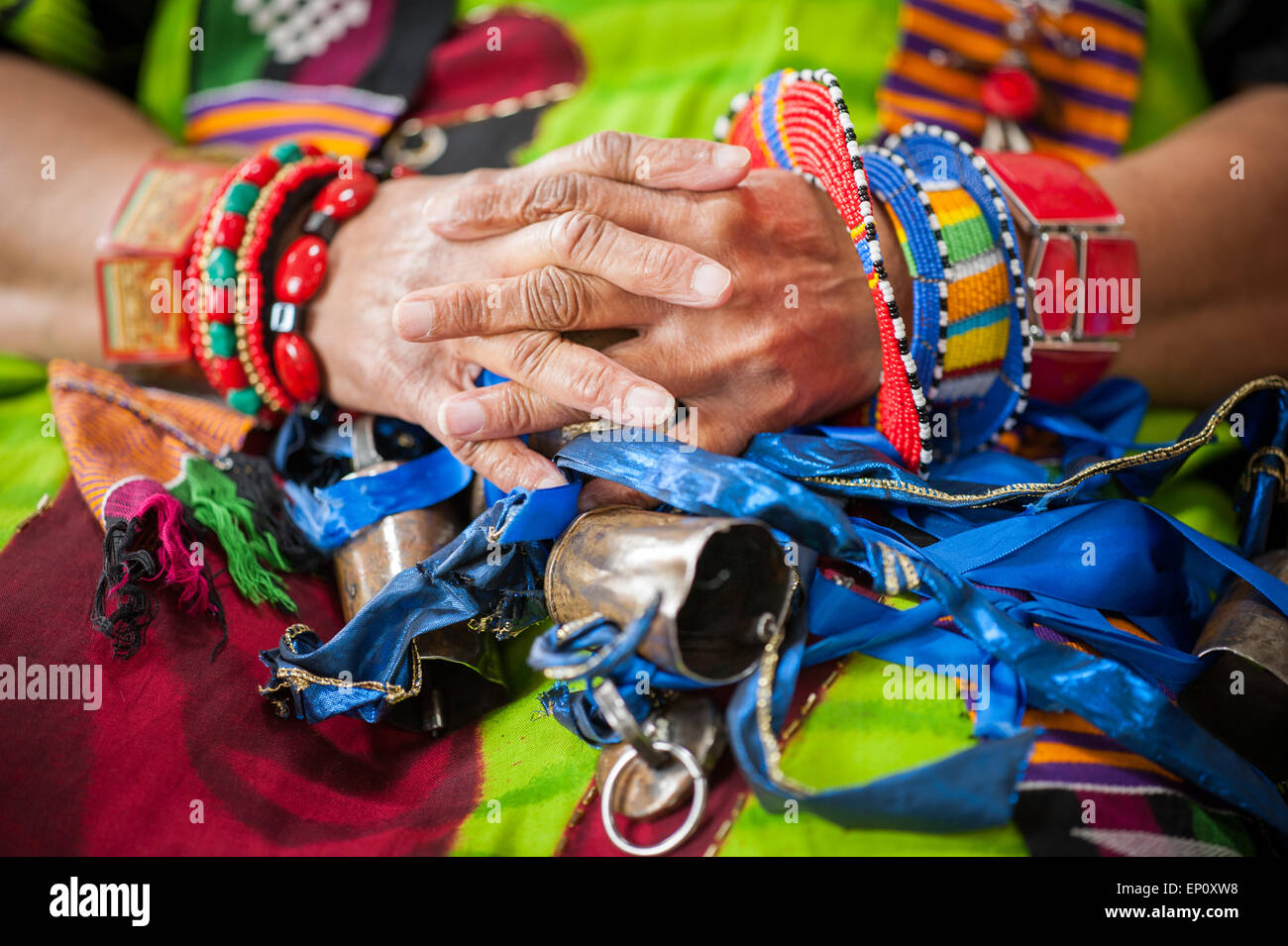 African American woman's hands wearing colorful traditional clothes and bracelets in Baltimore, Maryland. On her lap are bells a Stock Photo