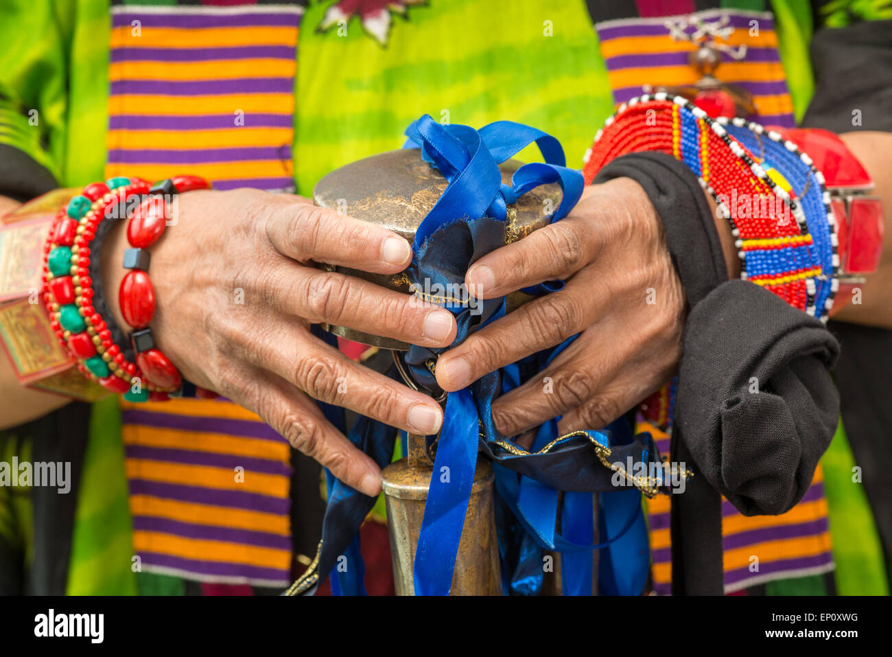 African American woman's hands holding bells with blue ribbons surrounded by traditional clothes and bracelets in Baltimore, Mar Stock Photo