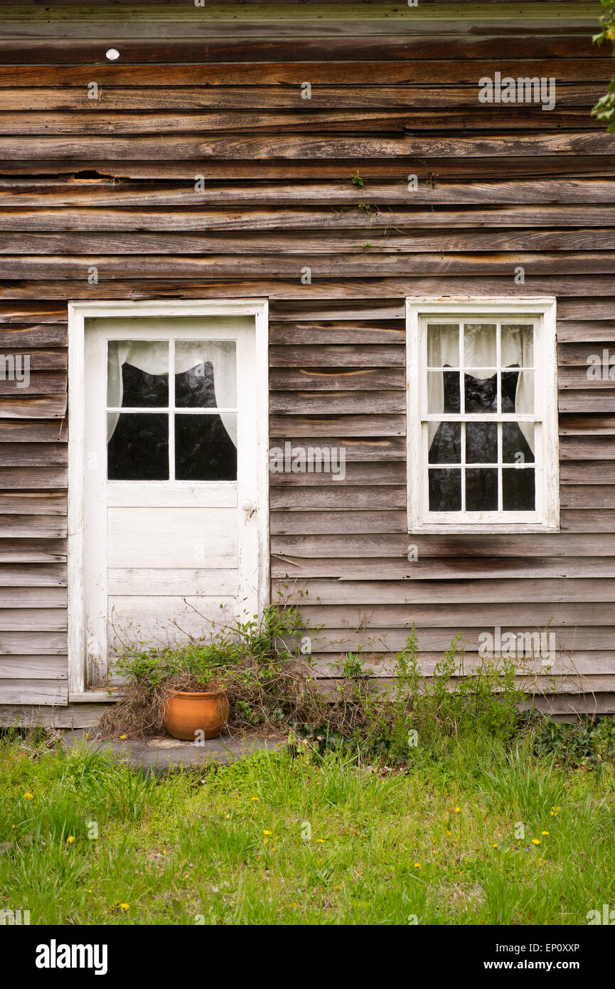 Close-up of house with old wooden siding and white painted door and window in Chrisfield, Maryland Stock Photo