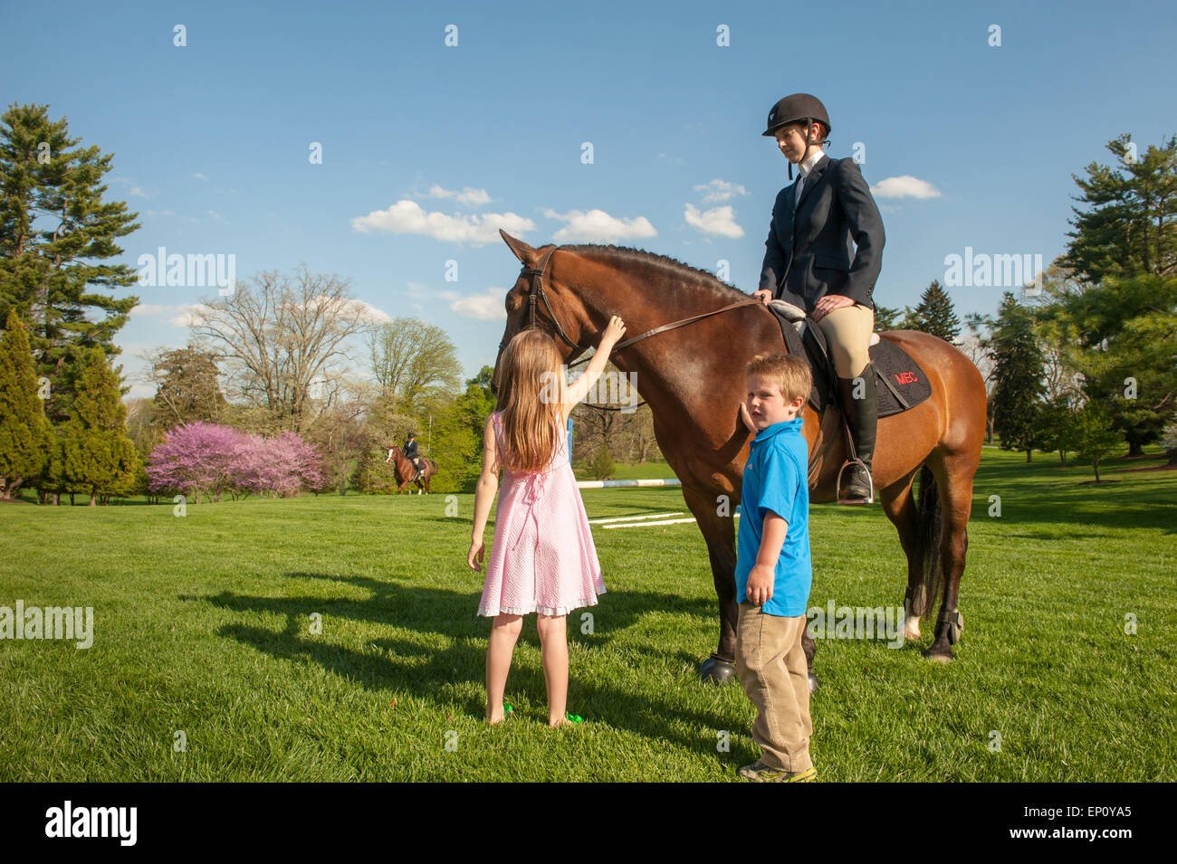 Woman sitting on a horse while a girl and a boy pet the horse in Baltimore County, MD USA Stock Photo