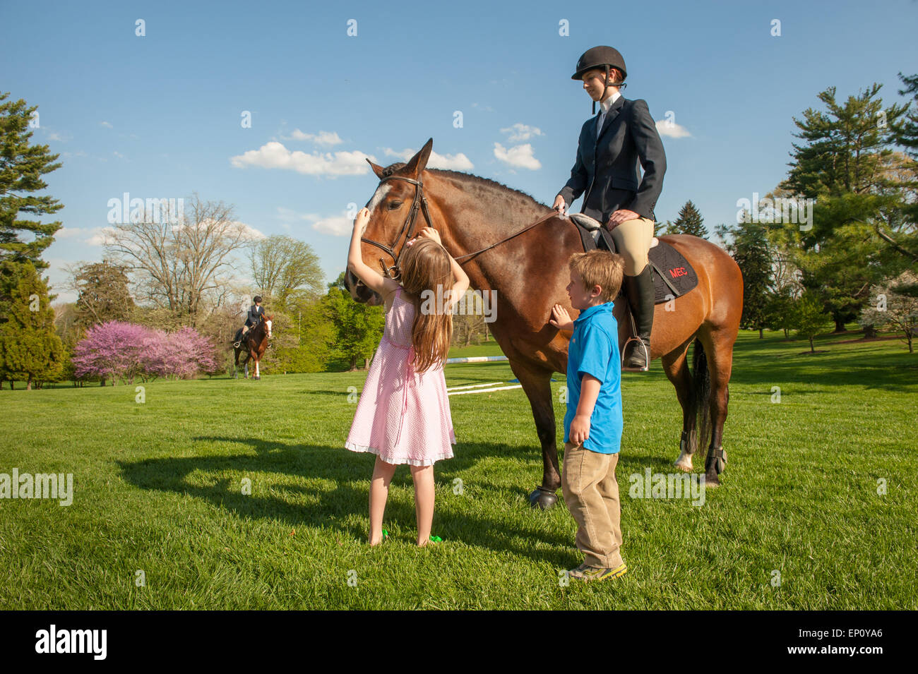 Woman sitting on a horse while a girl and a boy pet the horse in Baltimore County, MD USA Stock Photo