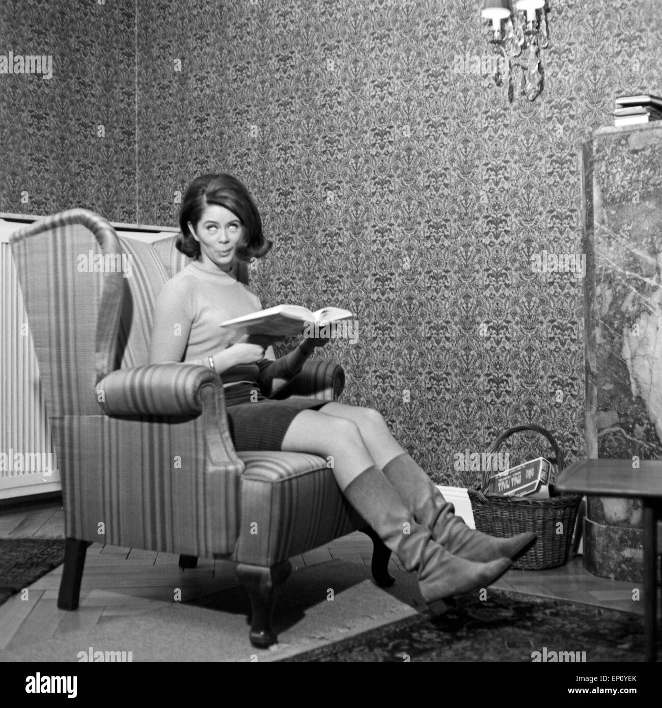 Norwegische Schlagersängerin Wencke Myhre sitzt im Wohnzimmersessel mit einem Buch, 1960er Jahre. Norwegian schlager singer Stock Photo