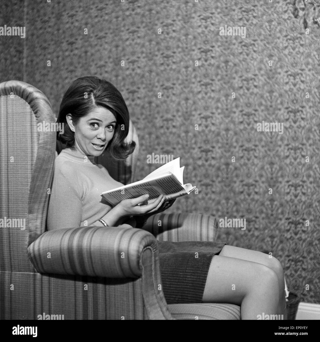 Norwegische Schlagersängerin Wencke Myhre sitzt im Wohnzimmersessel mit einem Buch, 1960er Jahre. Norwegian schlager singer Stock Photo