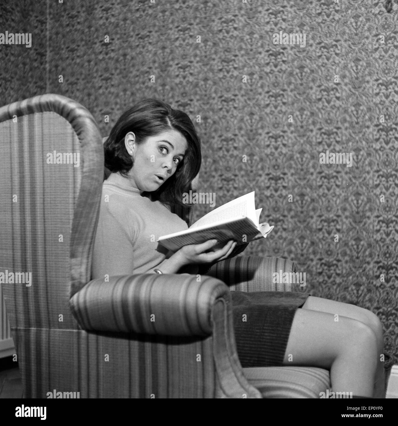 Norwegische Schlagersängerin Wencke Myhre sitzt im Wohnzimmersessel mit einem Buch, 1960er Jahre. Norwegian schlager singer Stock Photo