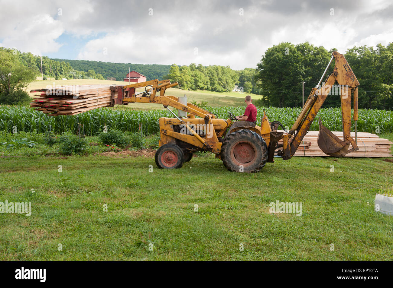 Man on a tractor moving lumber in Garrett County, Maryland, USA Stock Photo