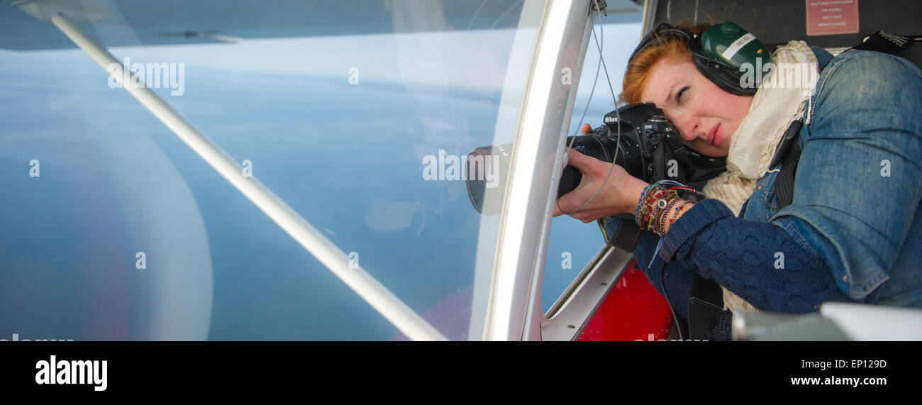 Woman photographer shooting aerials out of the window of a small plane in Maryland, USA Stock Photo