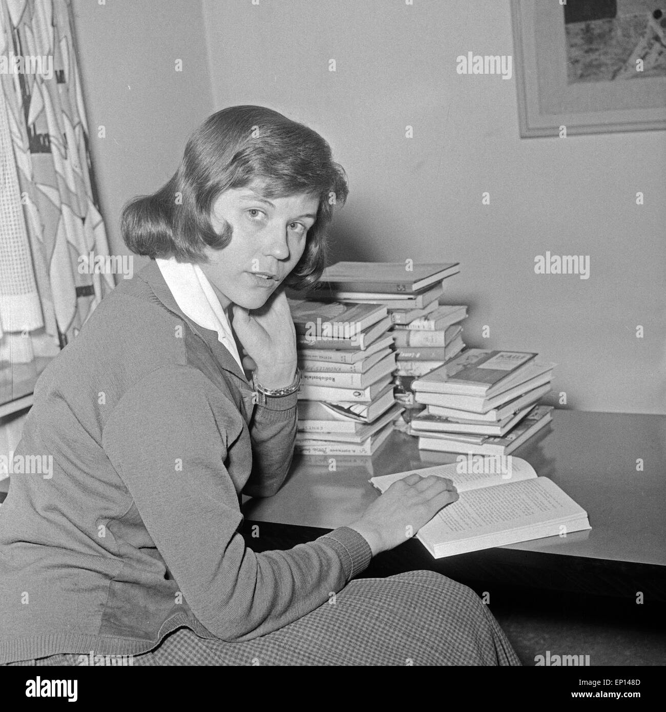 Eine junge Frau sitzt mit einem Stapel Bücher an einem Tisch, Deutschland 1950er Jahre. A young woman with a pile of books sitti Stock Photo