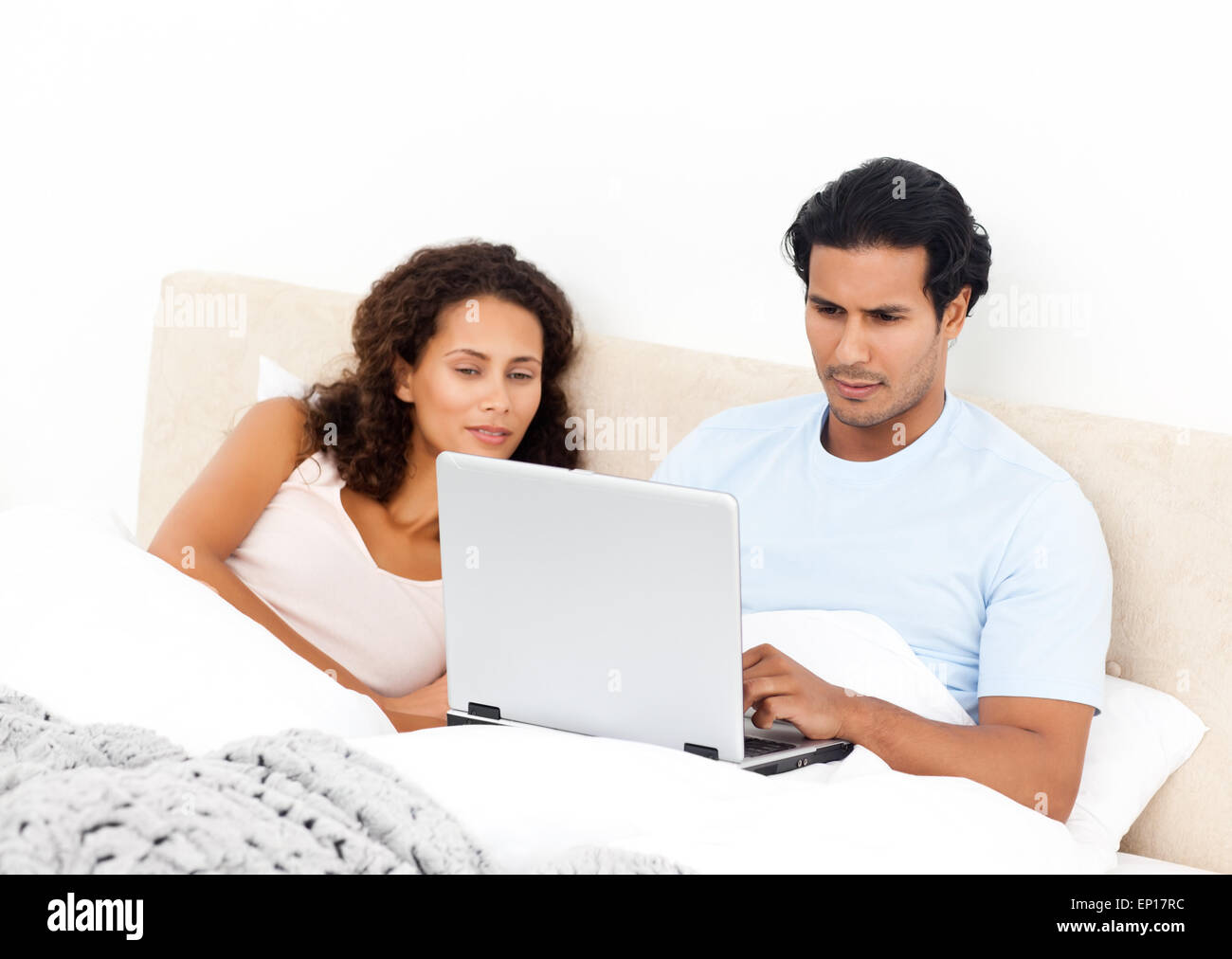 Serious man working on his laptop lying on his bed Stock Photo - Alamy