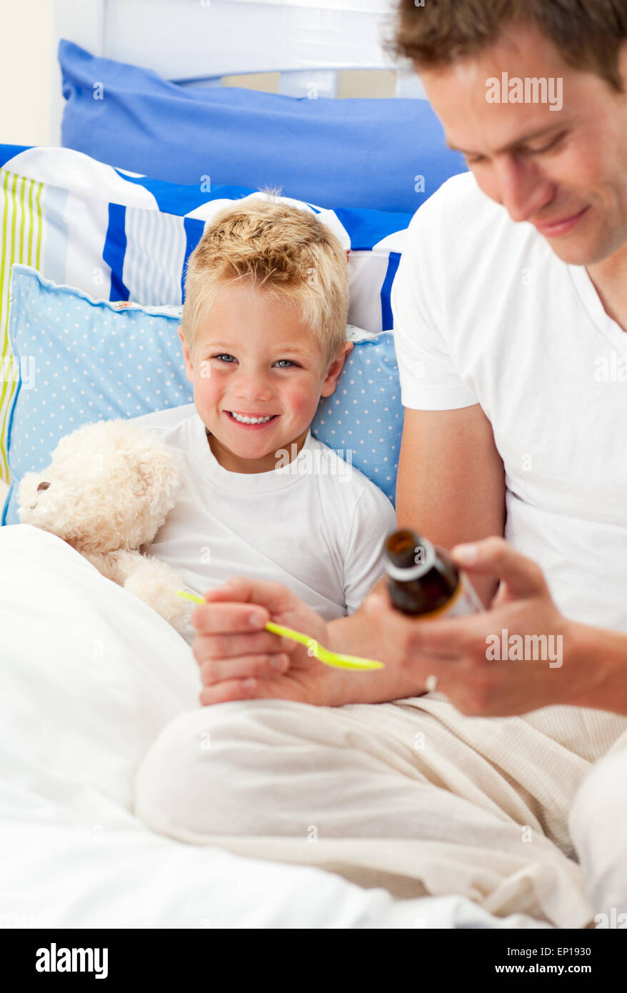 Smiling father giving cough syrup to his sick son Stock Photo
