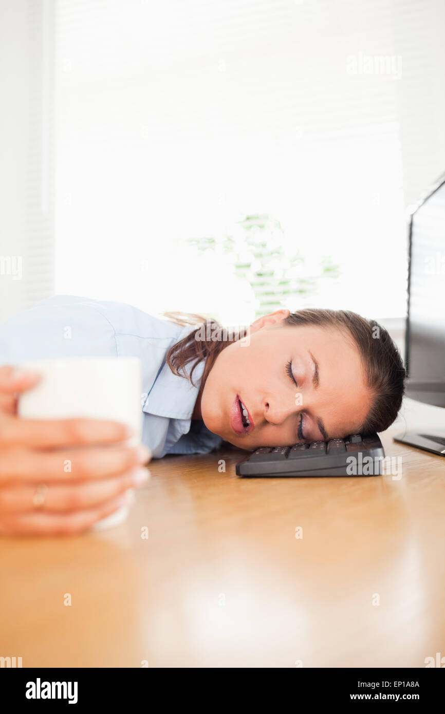 Sleeping businesswoman holding coffee in office Stock Photo - Alamy