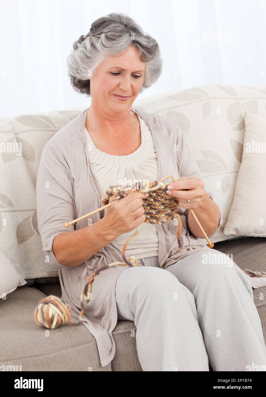 Senior woman knitting on her sofa Stock Photo - Alamy