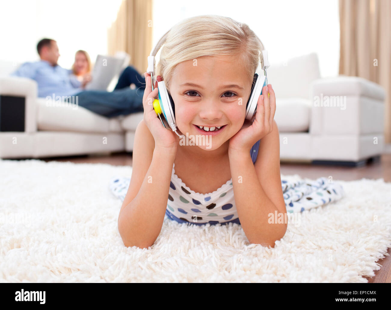 Happy little girl listening music lying on the floor Stock Photo - Alamy