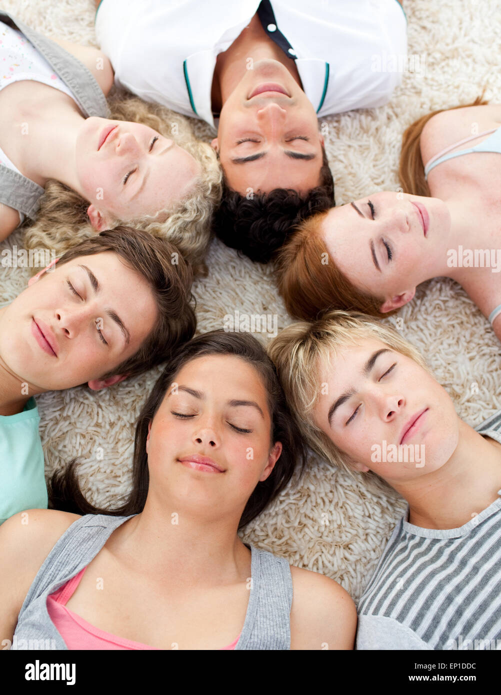 Teenagers with their heads together sleeping on the ground Stock Photo