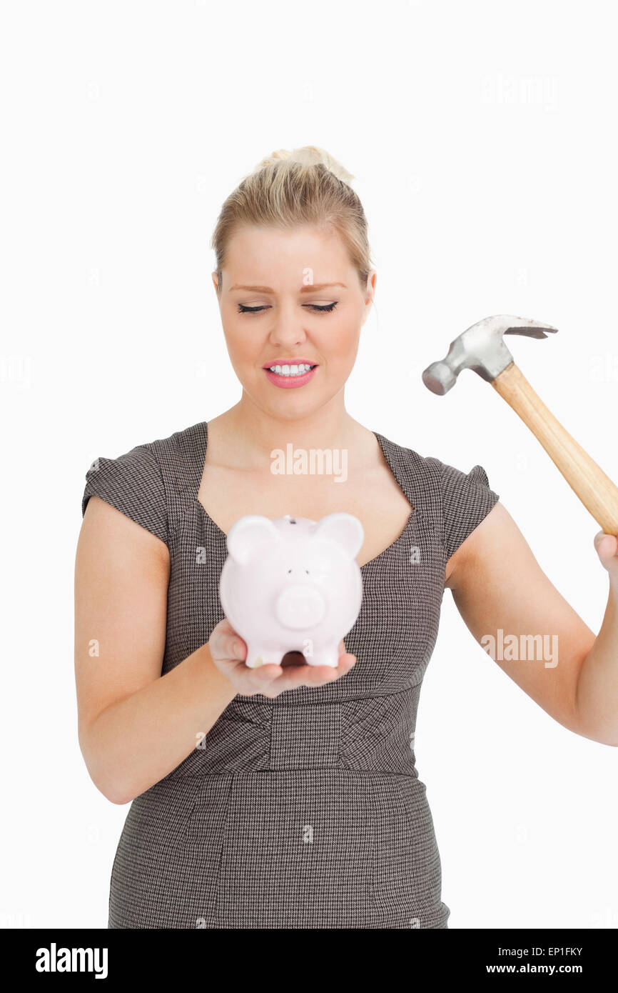 Serious woman with a piggy bank and a hammer Stock Photo - Alamy