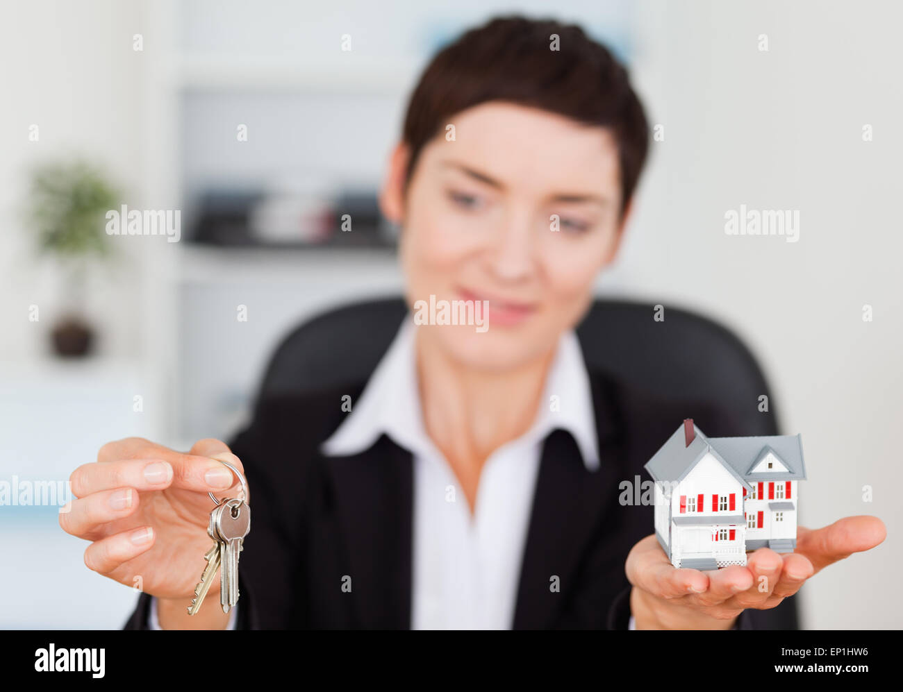 Businesswoman showing a miniature house and a key Stock Photo - Alamy